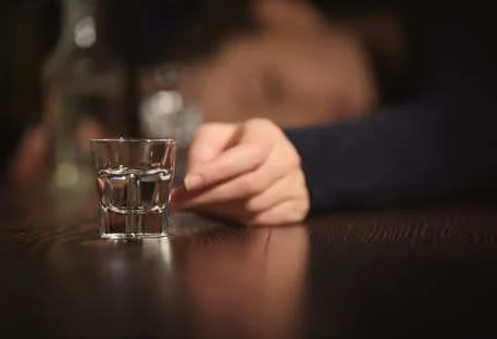 Стакан с алкоголем и спящий человек